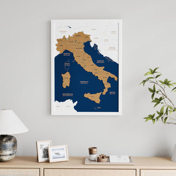 White-framed Italy cork wall map with Sardinia, Sicily and navy seas, above a sideboard with a lamp