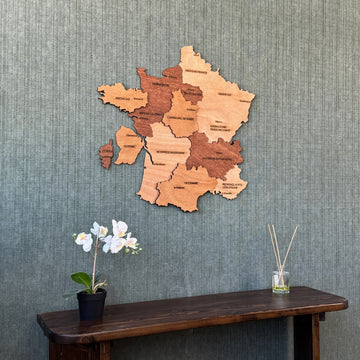 Wooden France map centered above a console with an orchid