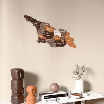 Soil Georgia wooden wall map on a beige wall above a console with figurines