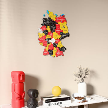 Flag colored Germany wooden wall map on a beige wall above a console with figurines
