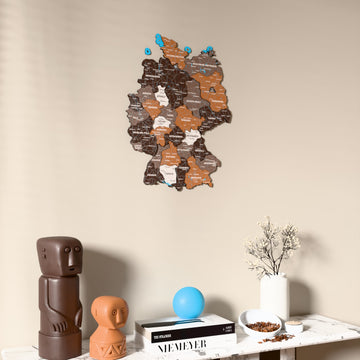 Soil Germany wooden wall map on a beige wall above a console with figurines