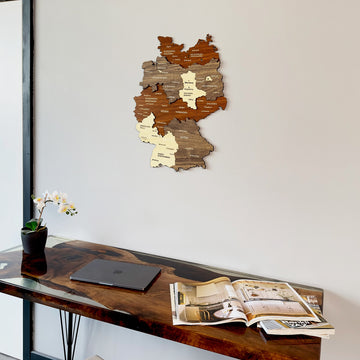 Wooden Germany map with cities, angled low view above a desk with an open magazine