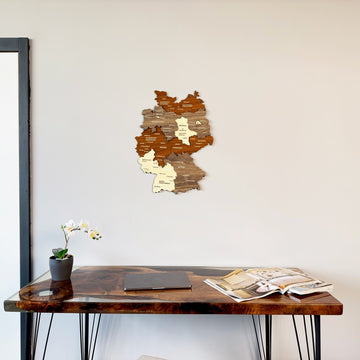 Multicolor 3D wooden Germany map with city names centered on the wall above a walnut desk