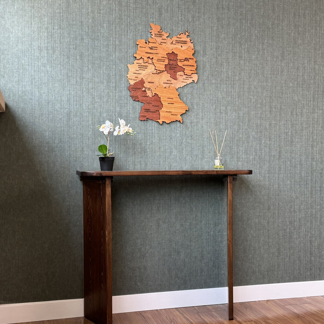 Germany wood wall map above a tall dark console, wide view with white baseboard