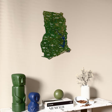 Satellite Ghana wooden wall map on a beige wall above a console with figurines