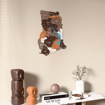 Soil Ghana wooden wall map on a beige wall above a console with figurines
