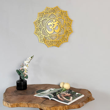 Gold OM mandala metal wall art above a live-edge wood table with a vase of flowers