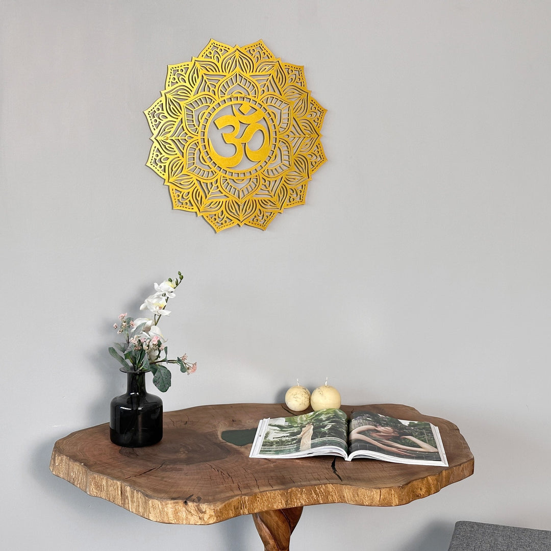 Gold OM mandala metal wall art centered over a live-edge table with two pears