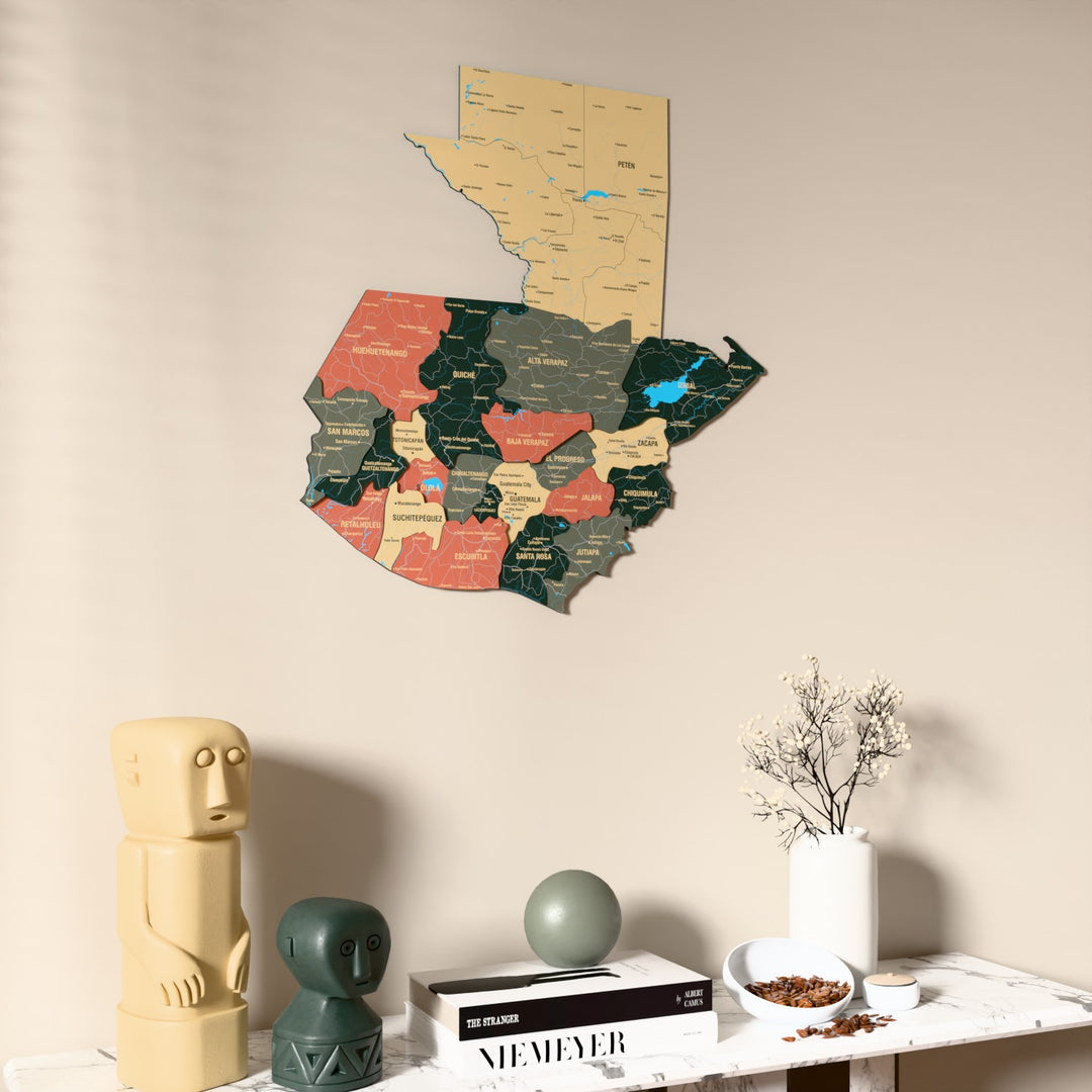 Sage Guatemala wooden wall map on a beige wall above a console with figurines