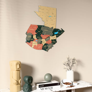 Sage Guatemala wooden wall map on a beige wall above a console with figurines