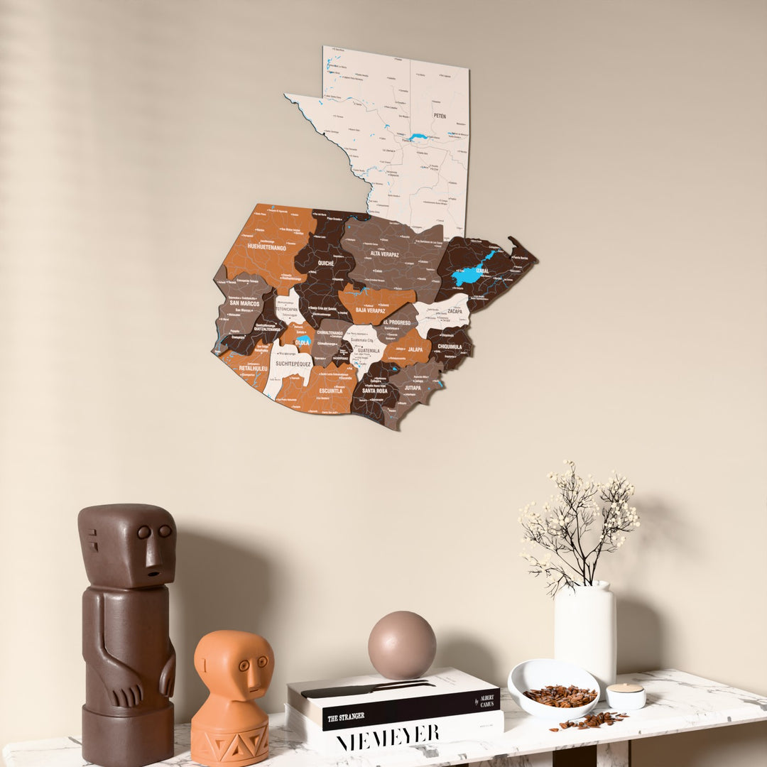 Soil Guatemala wooden wall map on a beige wall above a console with figurines