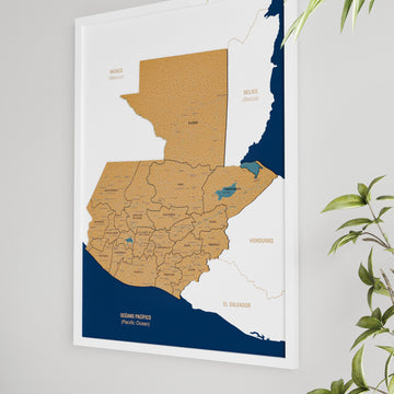 Side-angle view of a white-framed Guatemala cork wall map with the cork layer and a plant leaf at right