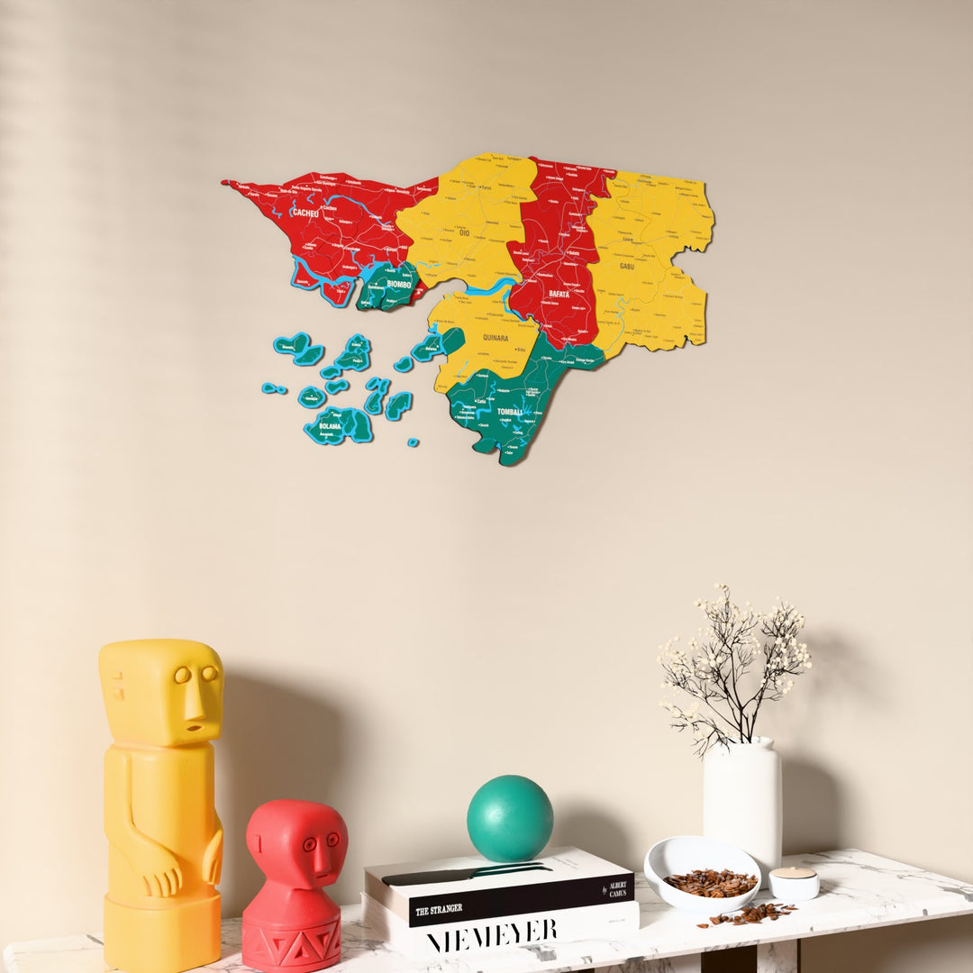 Flag colored Guinea-Bissau wooden wall map on a beige wall above a console with figurines