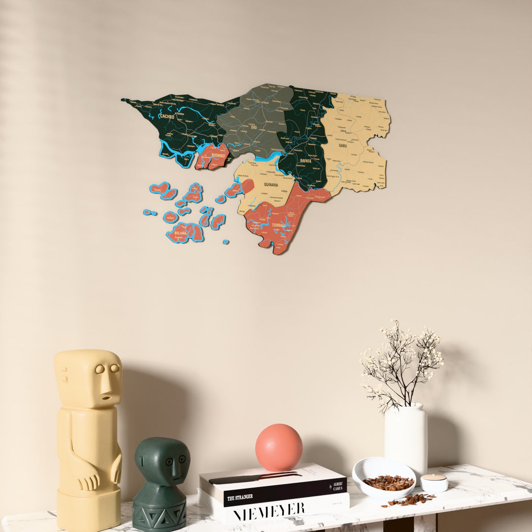 Sage Guinea-Bissau wooden wall map on a beige wall above a console with figurines