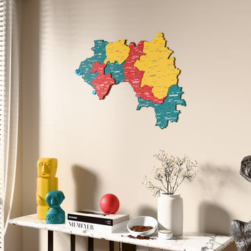 Flag colored Guinea wooden wall map beside a sheer curtain, angled view