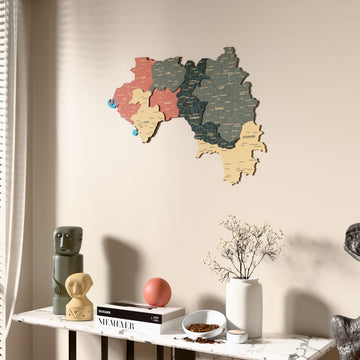 Sage Guinea wooden wall map beside a sheer curtain, angled view