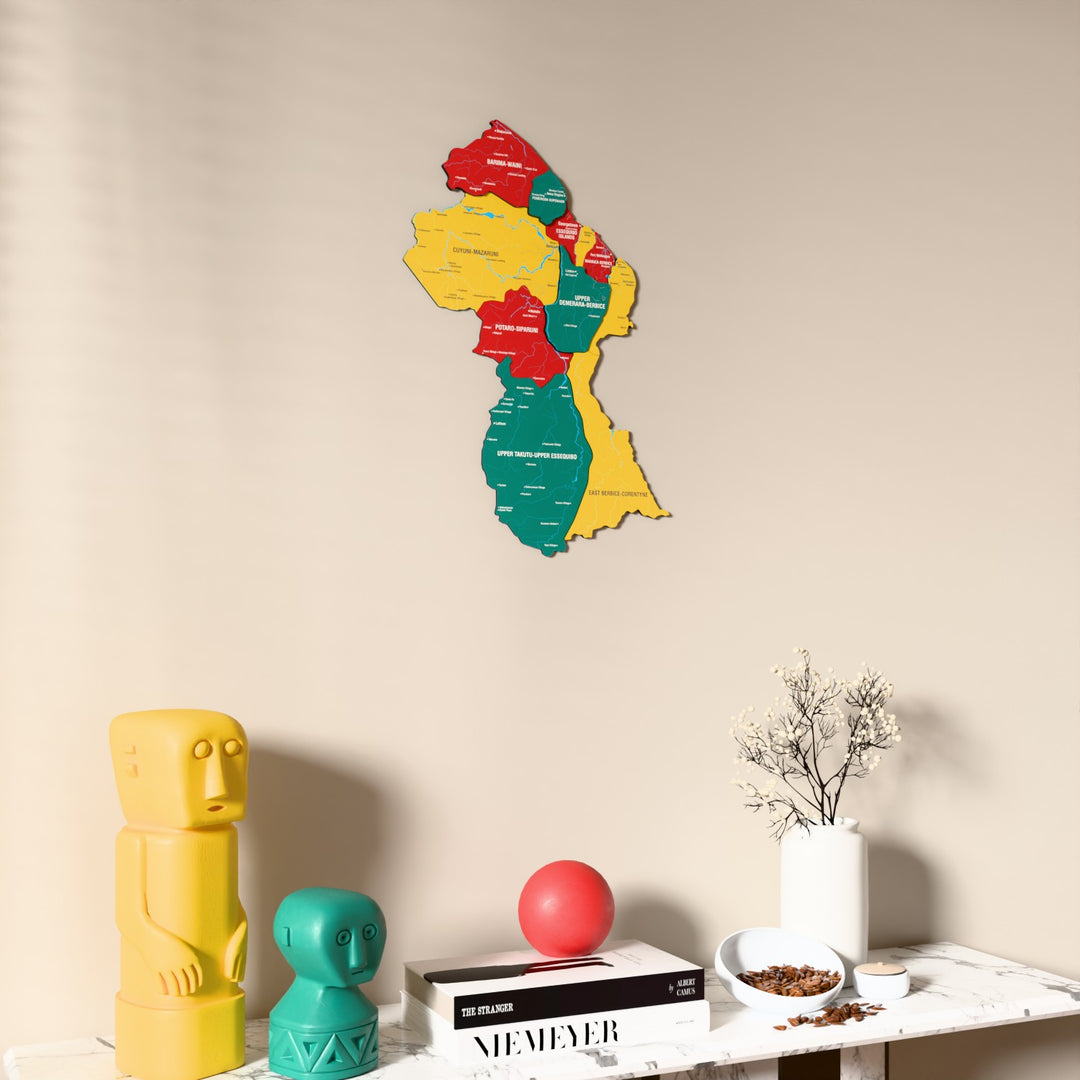 Flag colored Guyana wooden wall map on a beige wall above a console with figurines