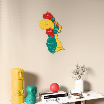 Flag colored Guyana wooden wall map on a beige wall above a console with figurines