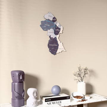 Nimbus Guyana wooden wall map on a beige wall above a console with figurines