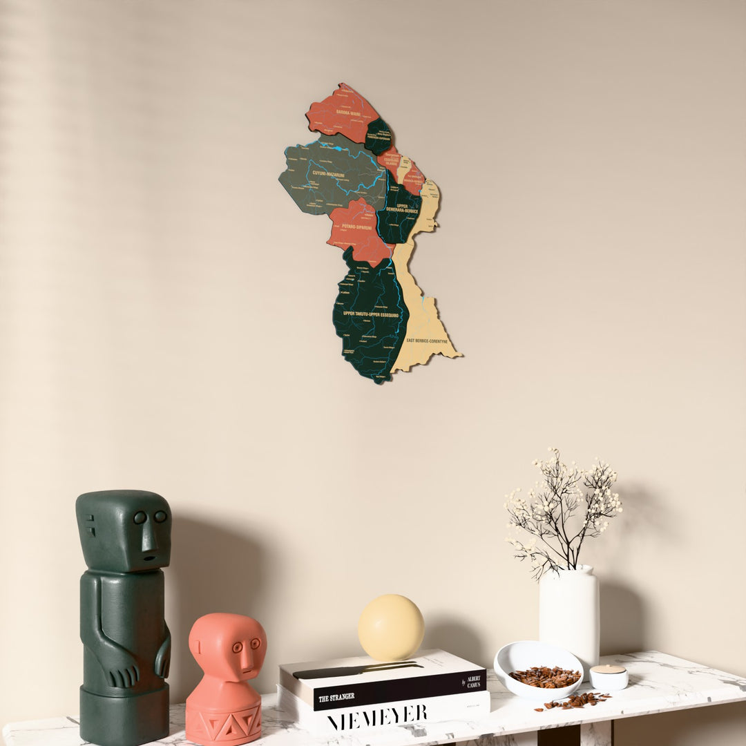 Sage Guyana wooden wall map on a beige wall above a console with figurines