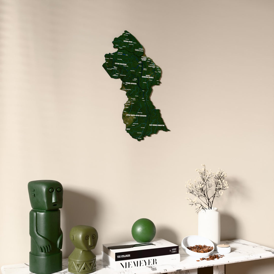 Satellite Guyana wooden wall map on a beige wall above a console with figurines