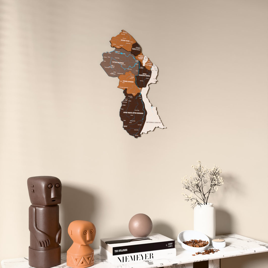 Soil Guyana wooden wall map on a beige wall above a console with figurines