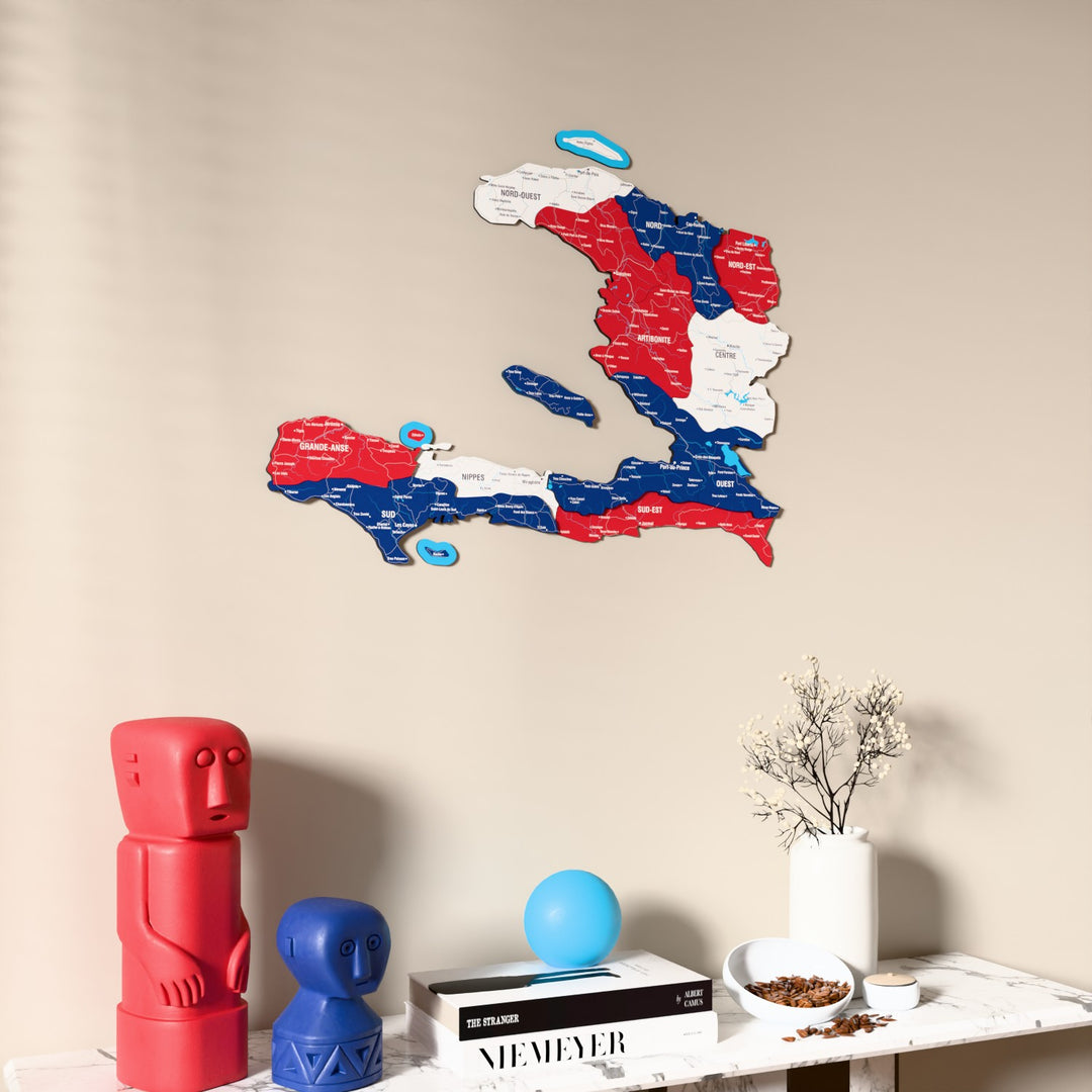 Flag colored Haiti wooden wall map on a beige wall above a console with figurines