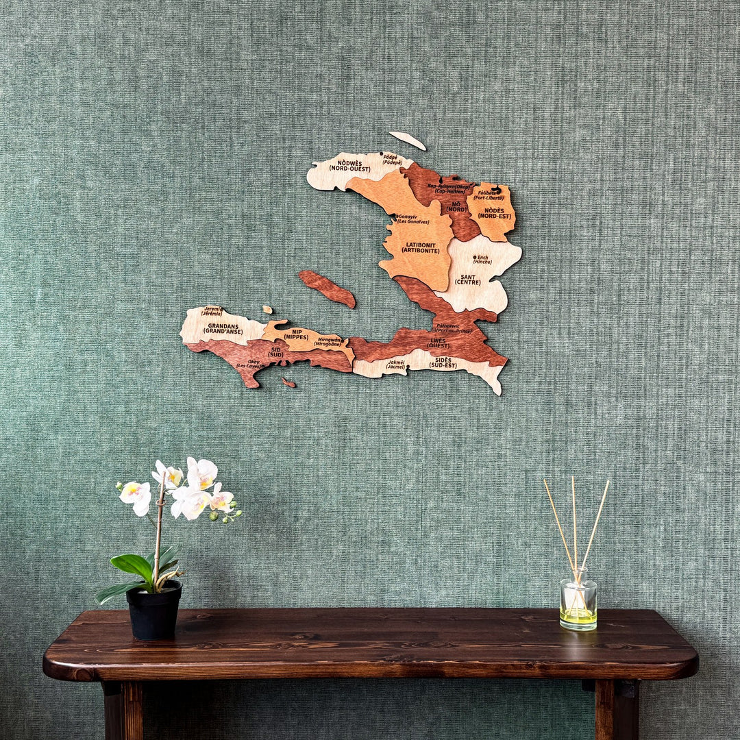 Wooden Haiti wall map with department names in layered plywood, above a console table