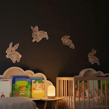 Hopping bunnies metal wall art in a dark nursery with cloud shelves and a night light
