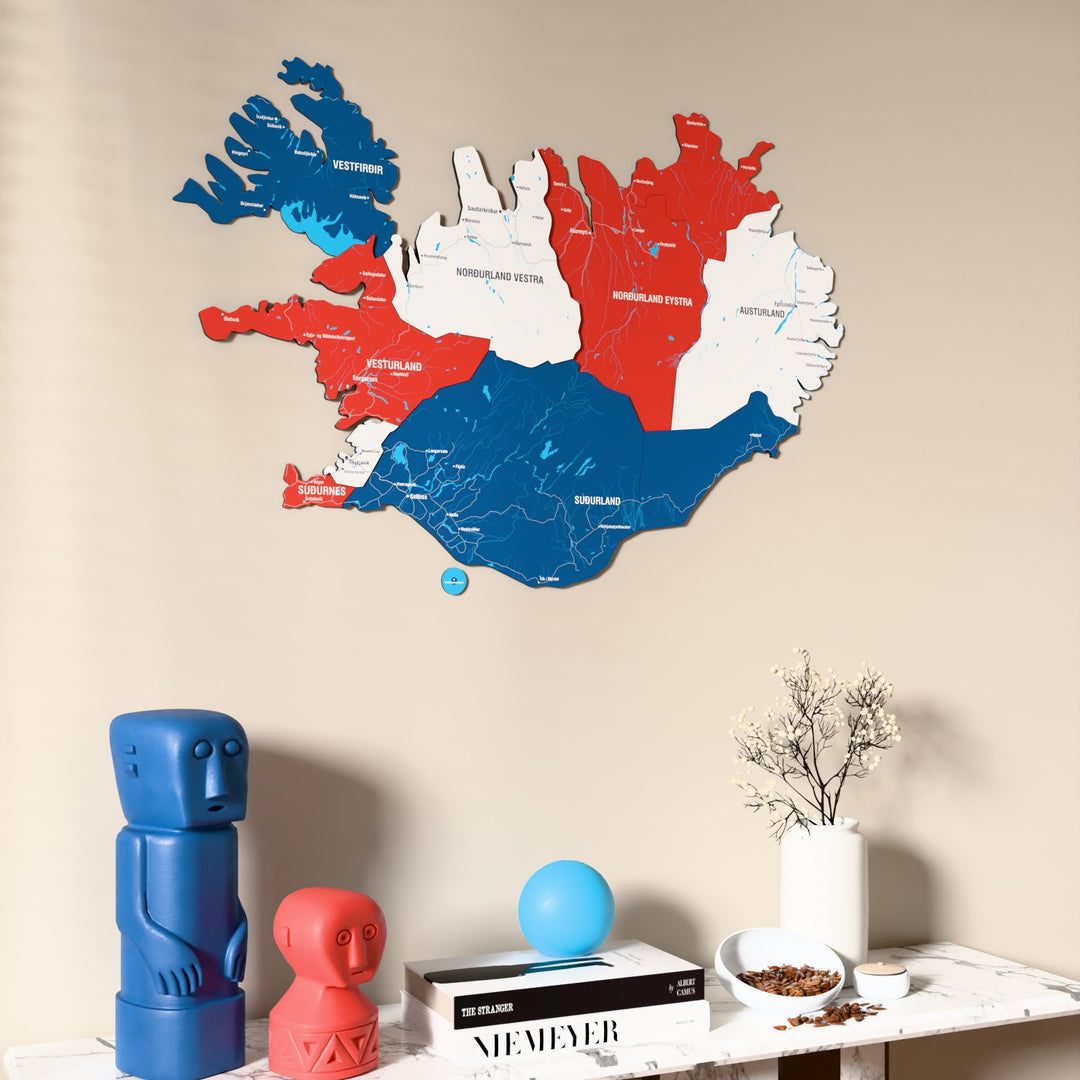 Flag colored Iceland wooden wall map on a beige wall above a console with figurines
