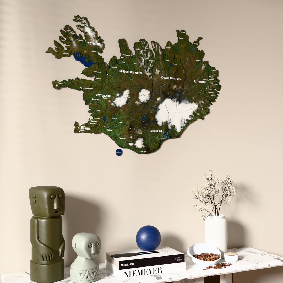 Satellite Iceland wooden wall map on a beige wall above a console with figurines