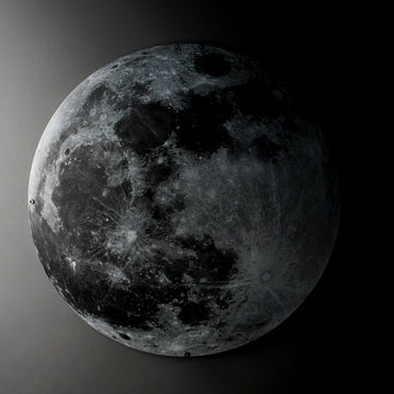 Close view of the UV printed metal Moon wall art in a dark room with a dramatic light gradient