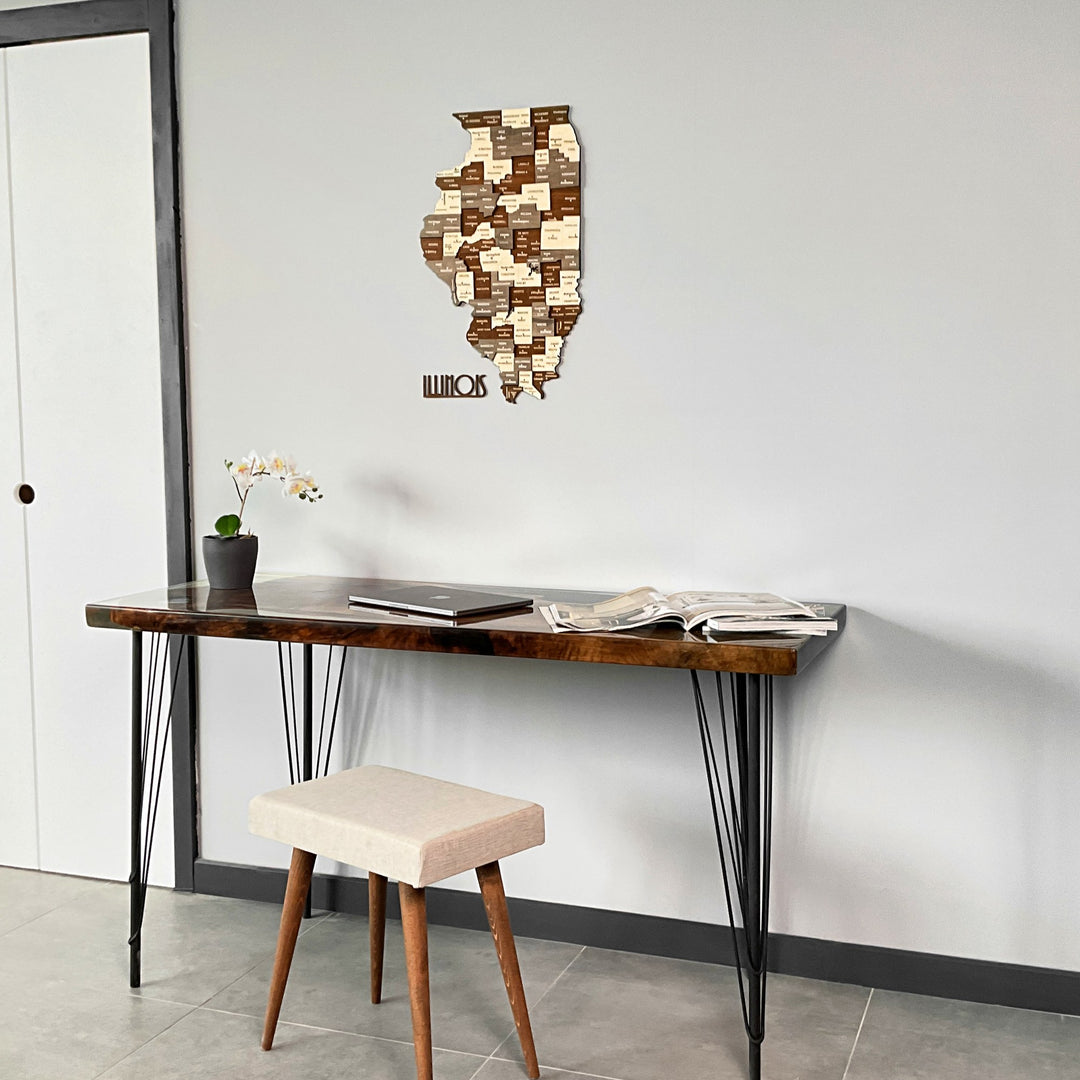 Layered wooden Illinois map at the top of a wide shot with a desk and white stool