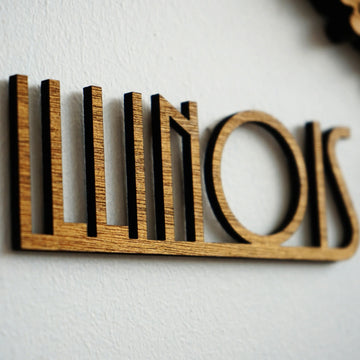 Close-up of the ILLINOIS name cut from wood in an art deco style lettering on a white wall