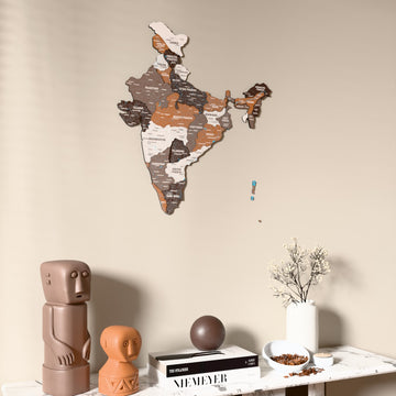Soil India wooden wall map on a beige wall above a console with figurines