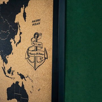 Close-up of the personalized anchor engraving on the framed cork world map, near the Pacific Ocean