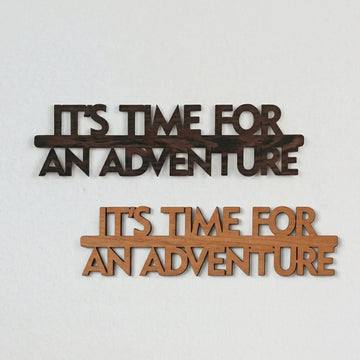 Wooden It's Time for an Adventure wall lettering in dark and light wood tones on a pale gray wall