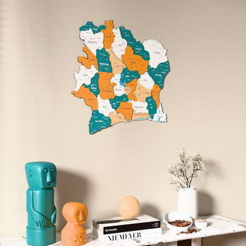 Flag colored Ivory Coast wooden wall map on a beige wall above a console with figurines
