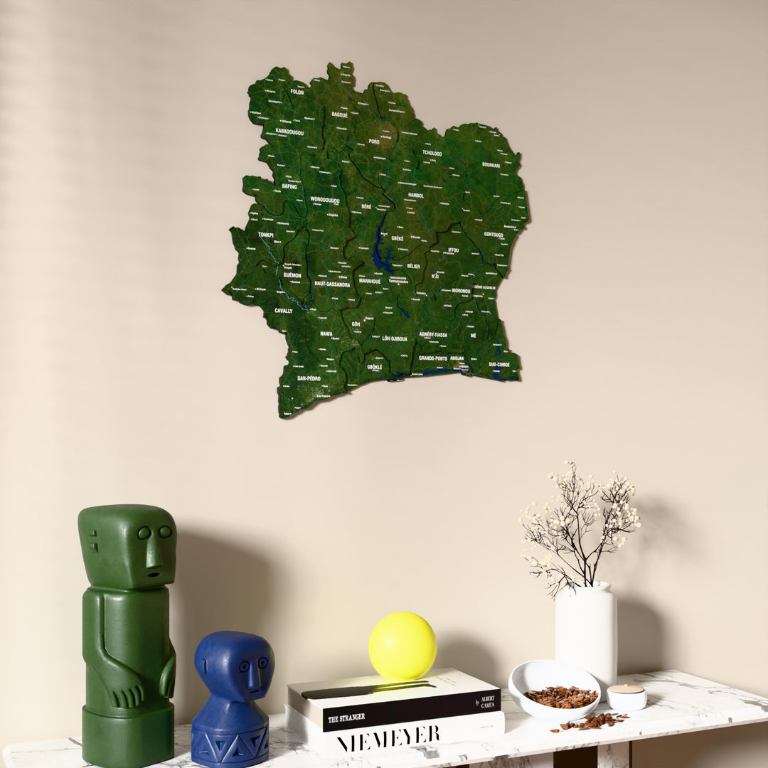 Satellite Ivory Coast wooden wall map on a beige wall above a console with figurines