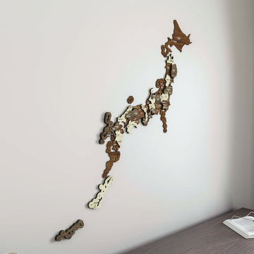 Large wooden Japan map from Hokkaido to Okinawa on a white wall, with a desk edge and open book at lower right