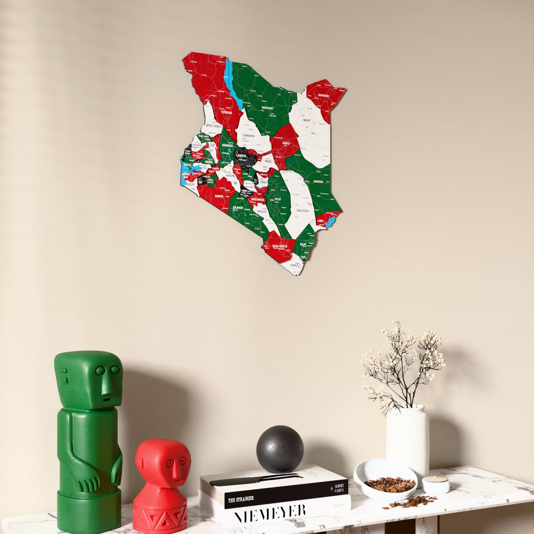 Flag colored Kenya wooden wall map on a beige wall above a console with figurines