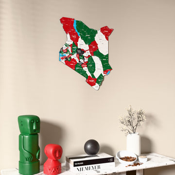 Flag colored Kenya wooden wall map on a beige wall above a console with figurines