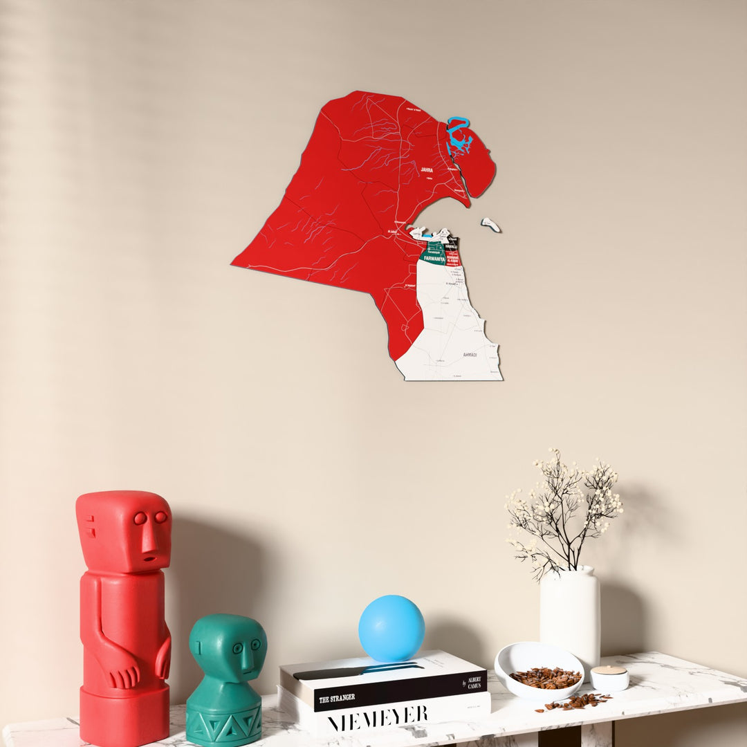 Flag colored Kuwait wooden wall map on a beige wall above a console with figurines