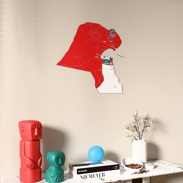 Flag colored Kuwait wooden wall map on a beige wall above a console with figurines