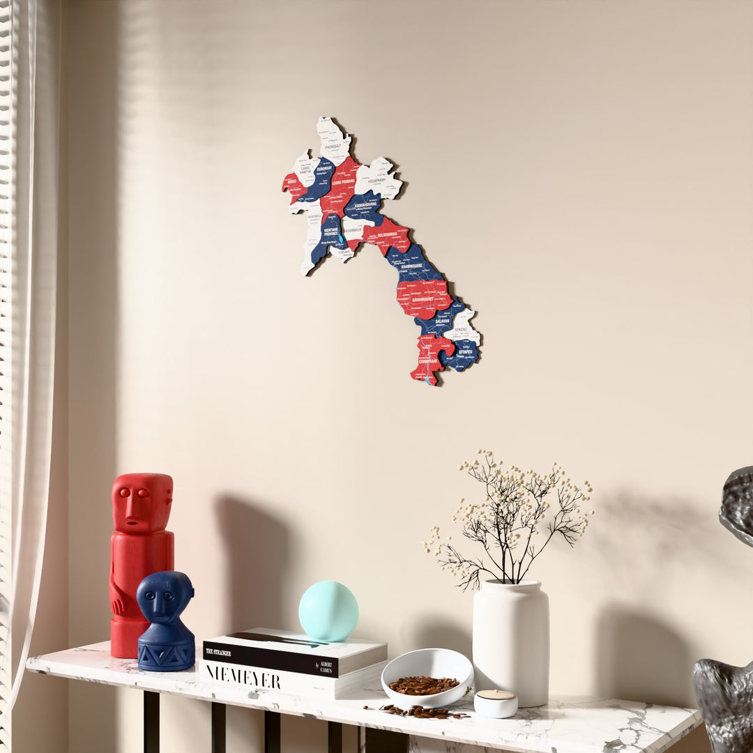 Flag colored Laos wooden wall map beside a sheer curtain, angled view