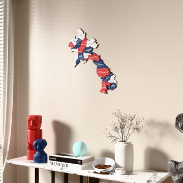 Flag colored Laos wooden wall map beside a sheer curtain, angled view