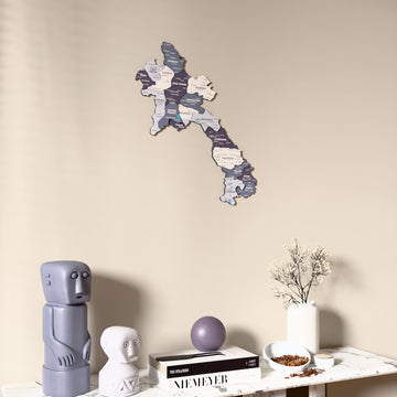Nimbus Laos wooden wall map on a beige wall above a console with figurines