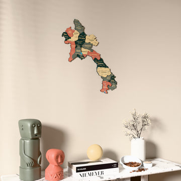 Sage Laos wooden wall map on a beige wall above a console with figurines