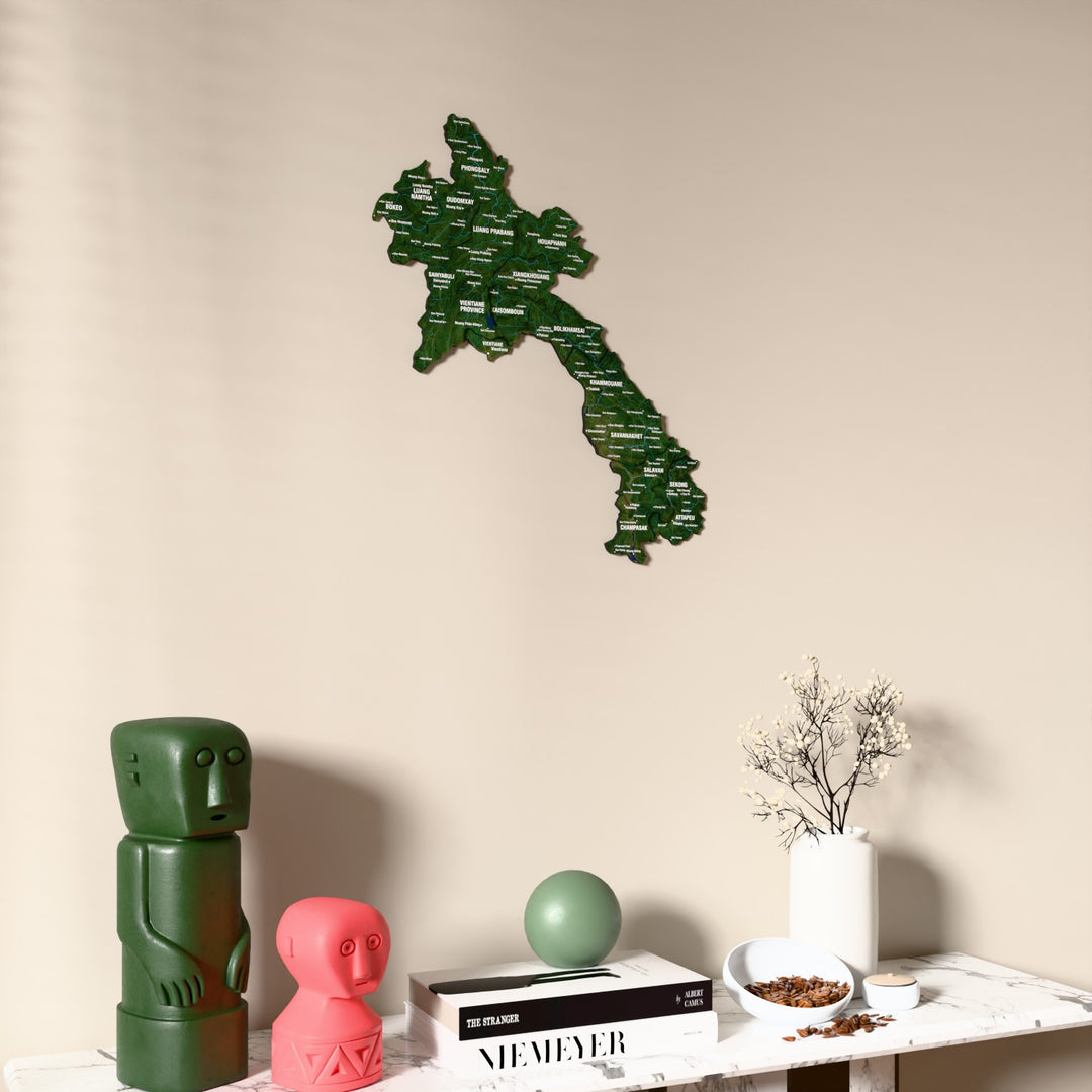 Satellite Laos wooden wall map on a beige wall above a console with figurines