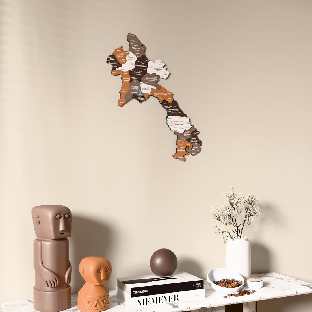 Soil Laos wooden wall map on a beige wall above a console with figurines